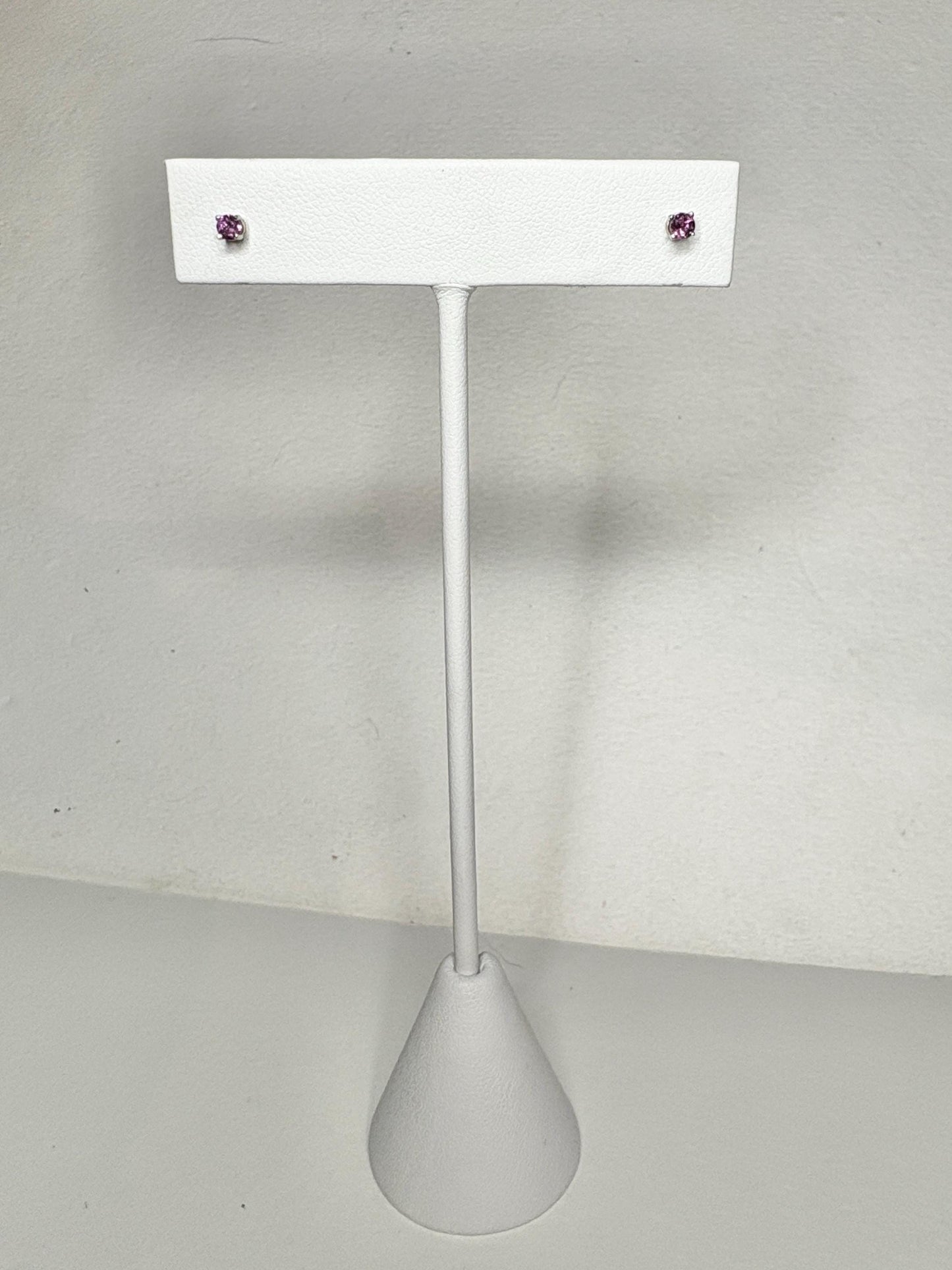 Two small, round rhodolite garnet stud earrings set in 14k white gold.