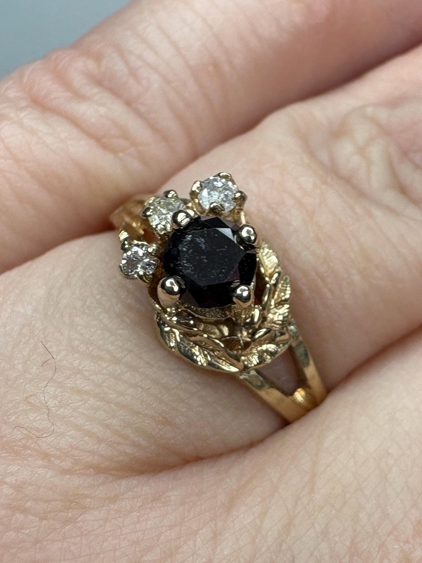 A 10k gold ring with a black diamond center and three white diamonds.