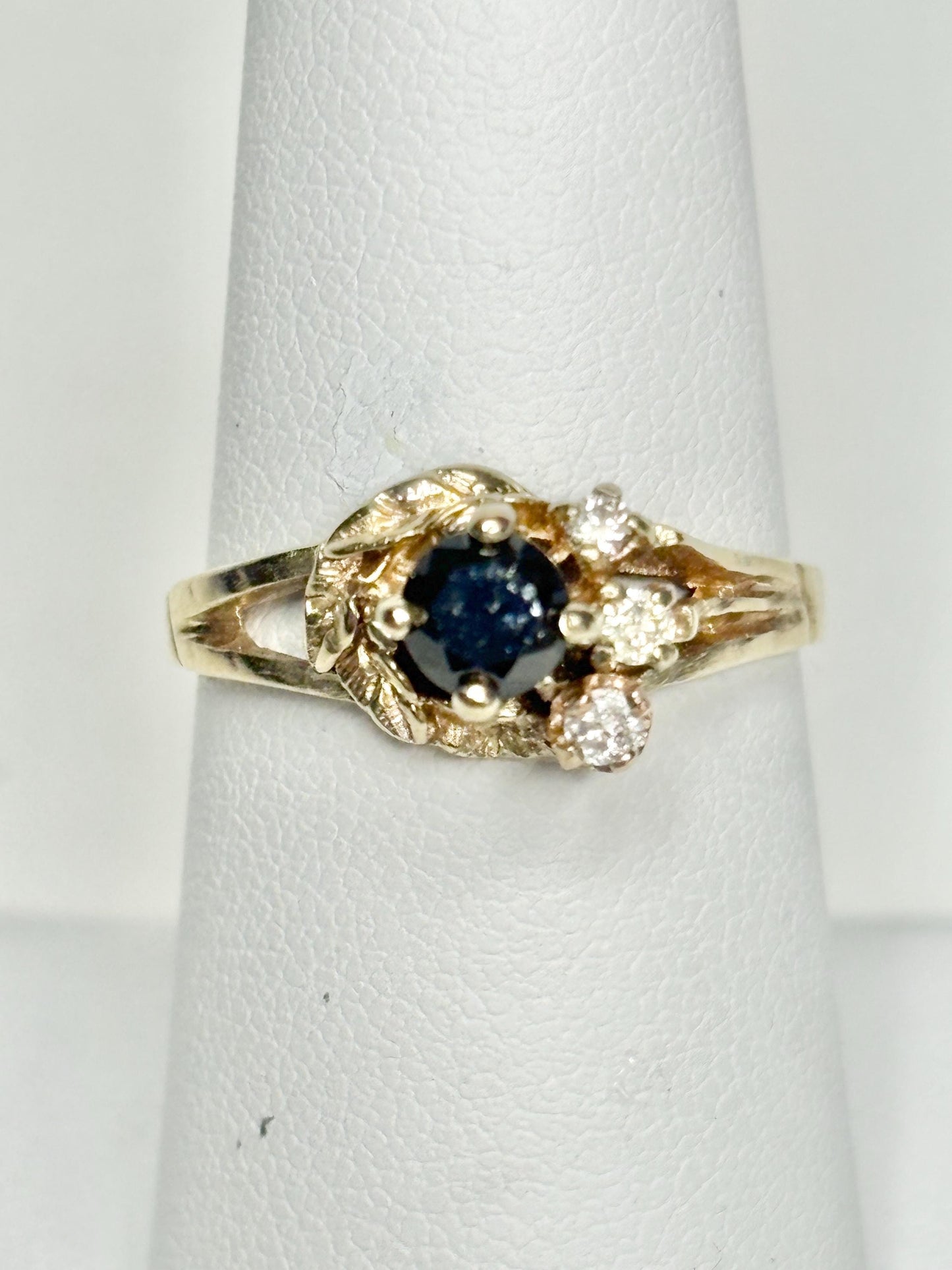 A 10k yellow gold ring with a black diamond center and three white diamonds.
