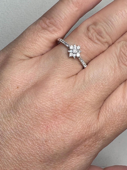 A 10k white gold ring with a starburst design of baguette and round diamonds.