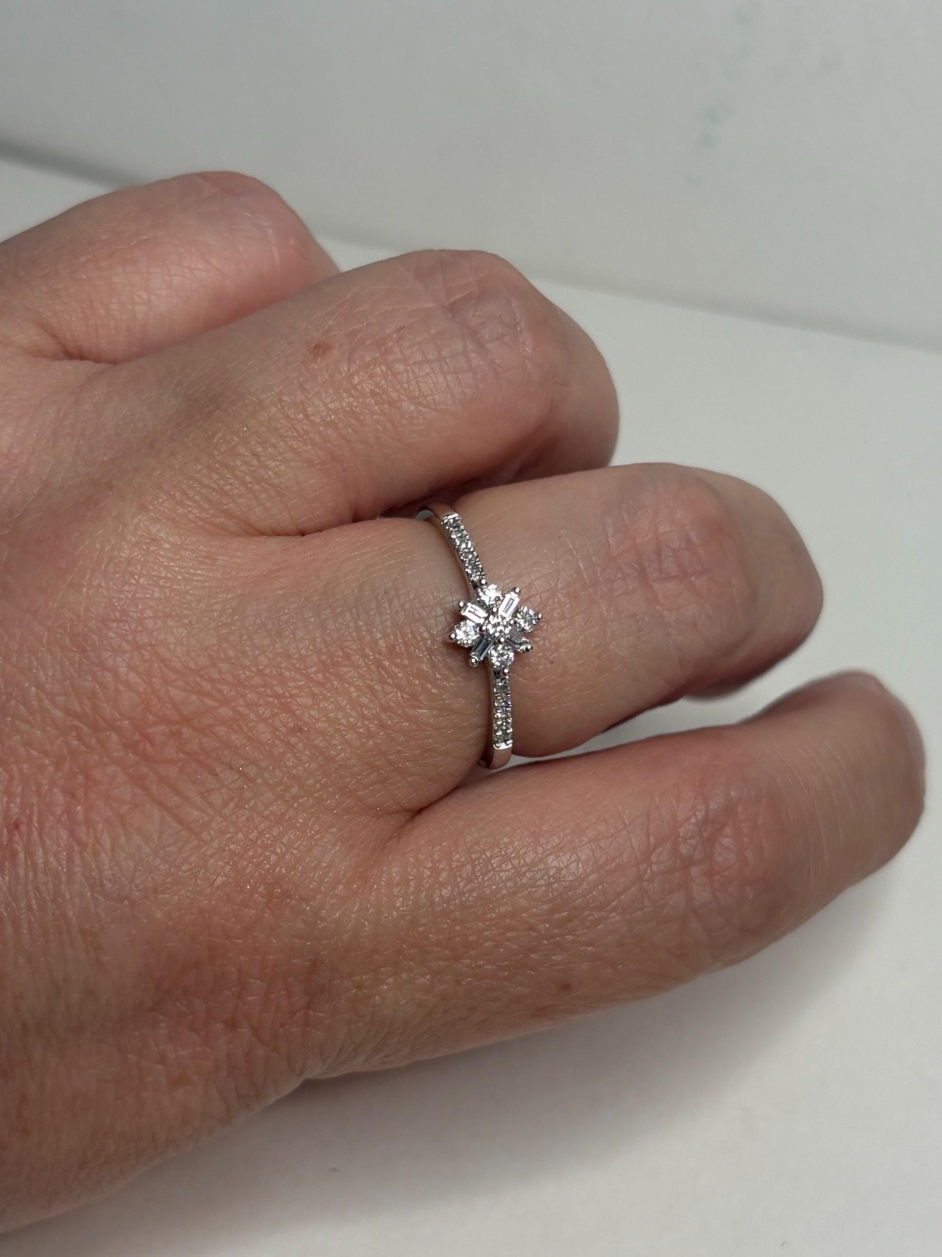 A white gold ring with a starburst design of baguette and round diamonds.