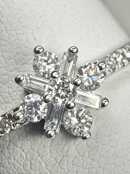 A white gold ring with a starburst design featuring baguette and round diamonds.