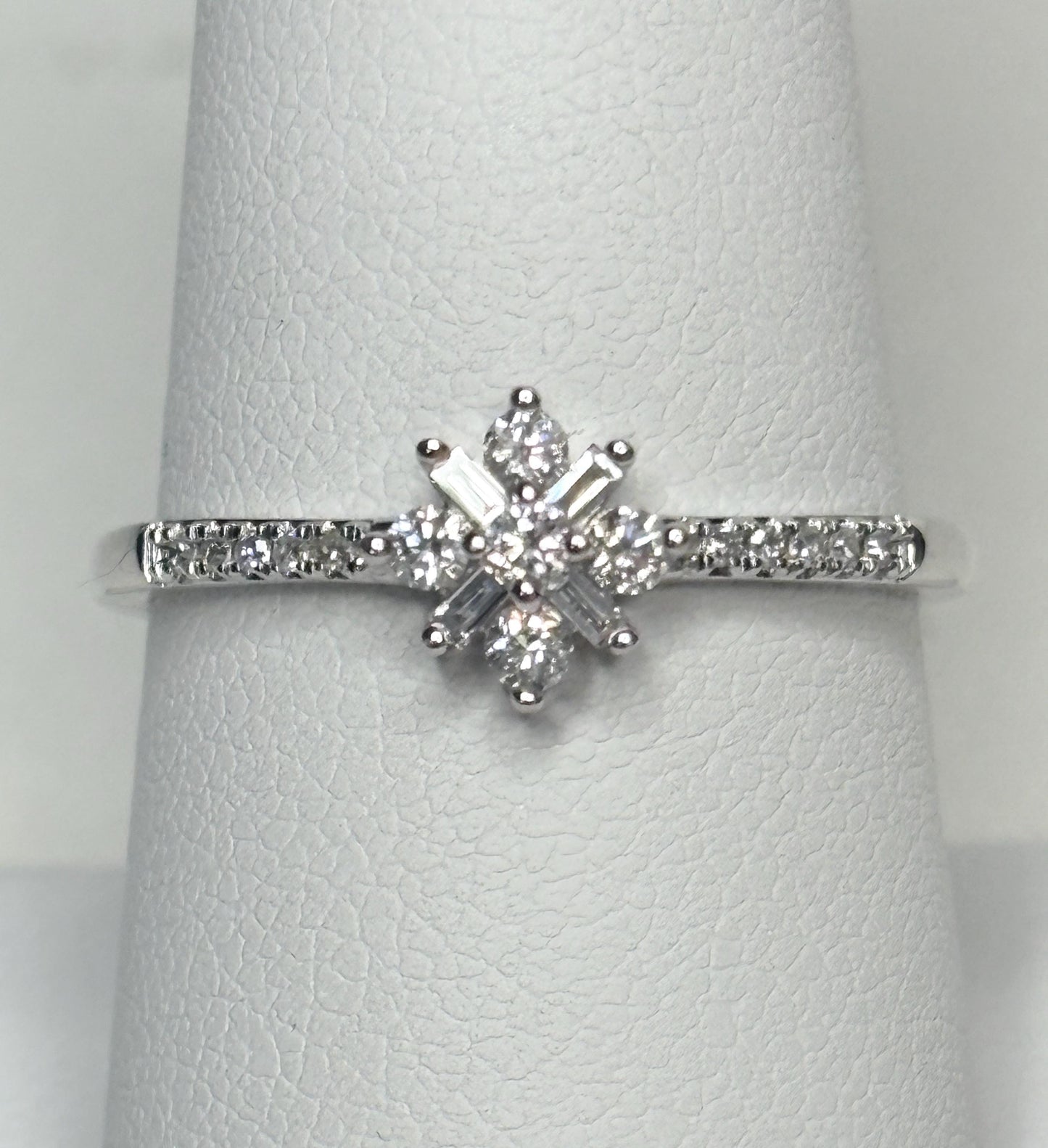 A white gold ring with a starburst design of baguette and round diamonds.