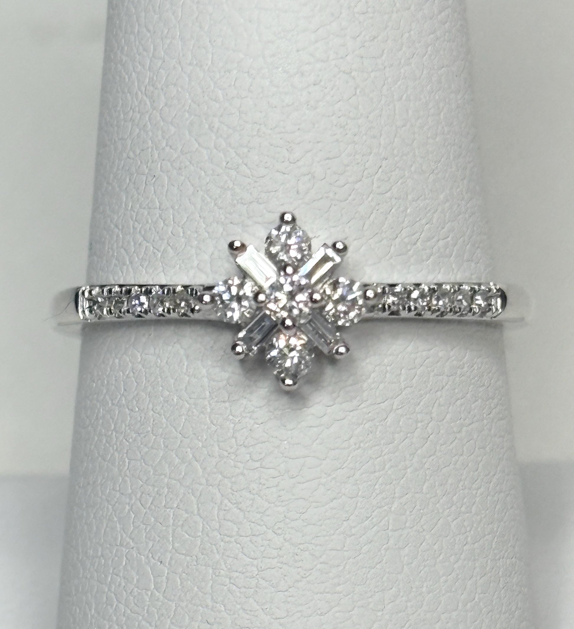 A white gold ring with a starburst design of baguette and round diamonds.