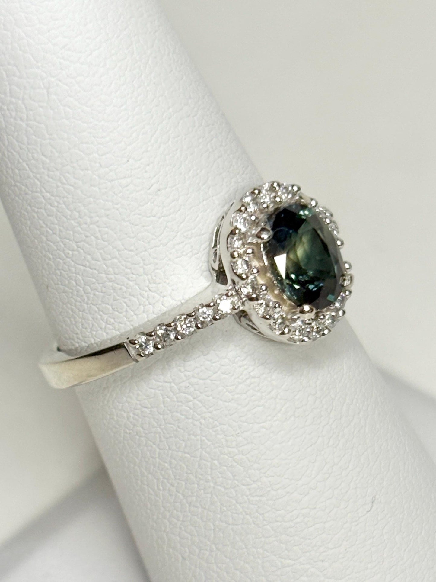 A 10k white gold ring with an oval bi-color sapphire surrounded by diamonds.