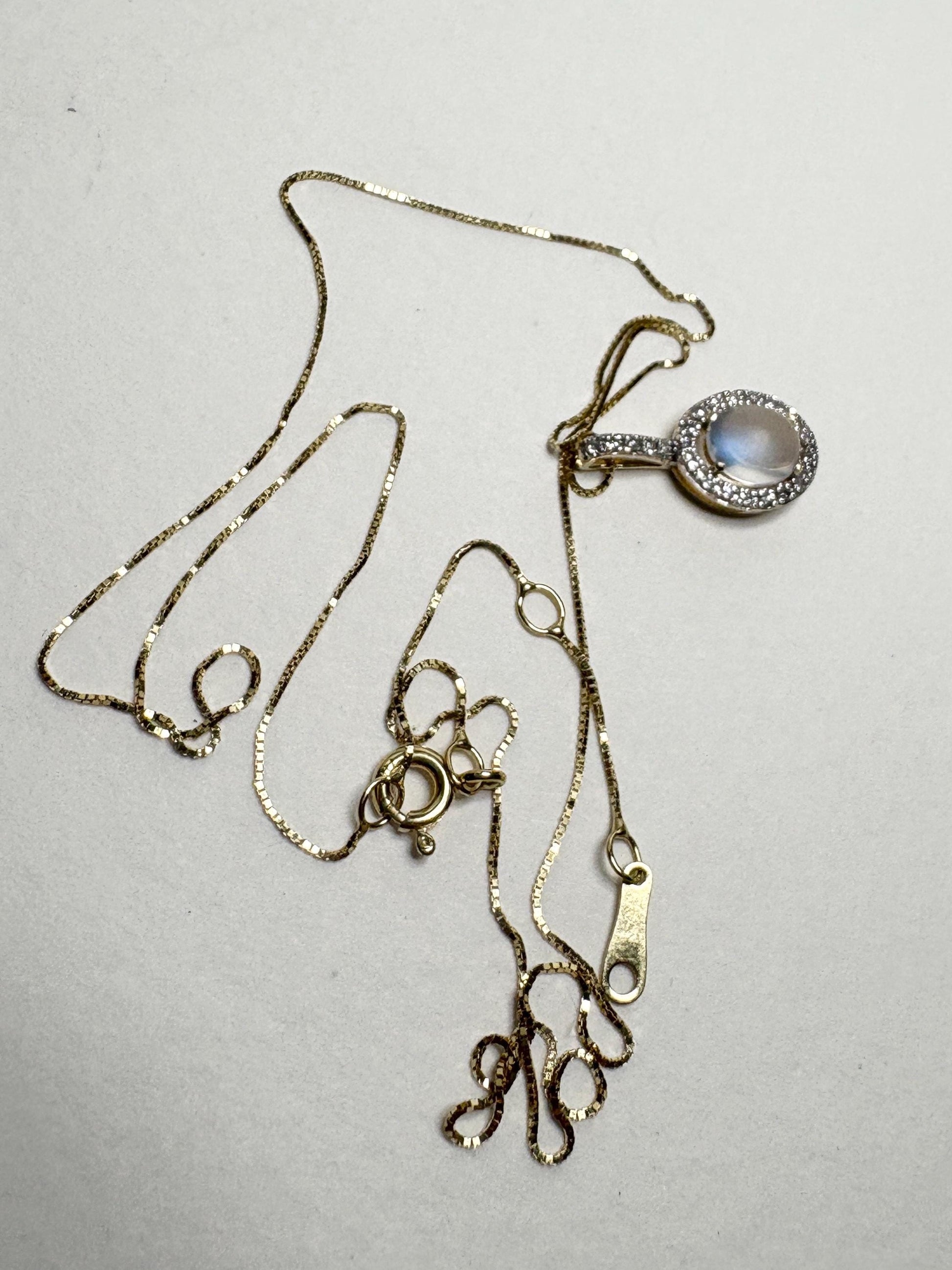 Gold necklace with a moonstone and diamond halo pendant.
