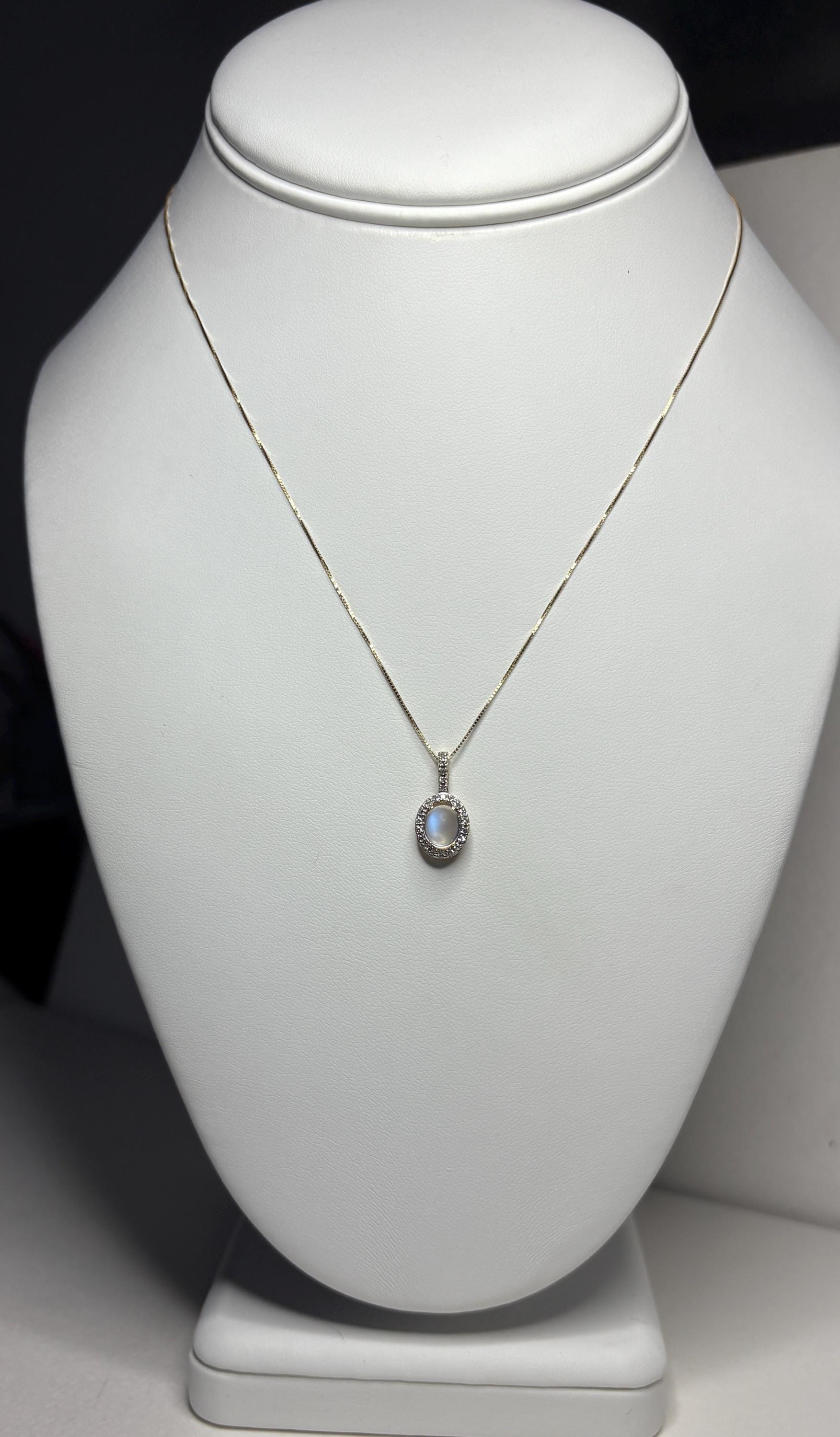 A 10k gold necklace with a blue sheen moonstone and diamond halo pendant.