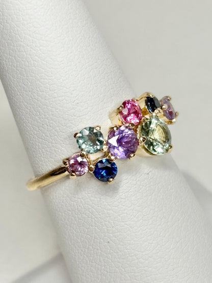 A 10k gold ring featuring a cluster of round multi-colored sapphires.