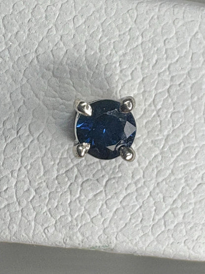 A round, dark blue sapphire is set in a 14k white gold stud earring.