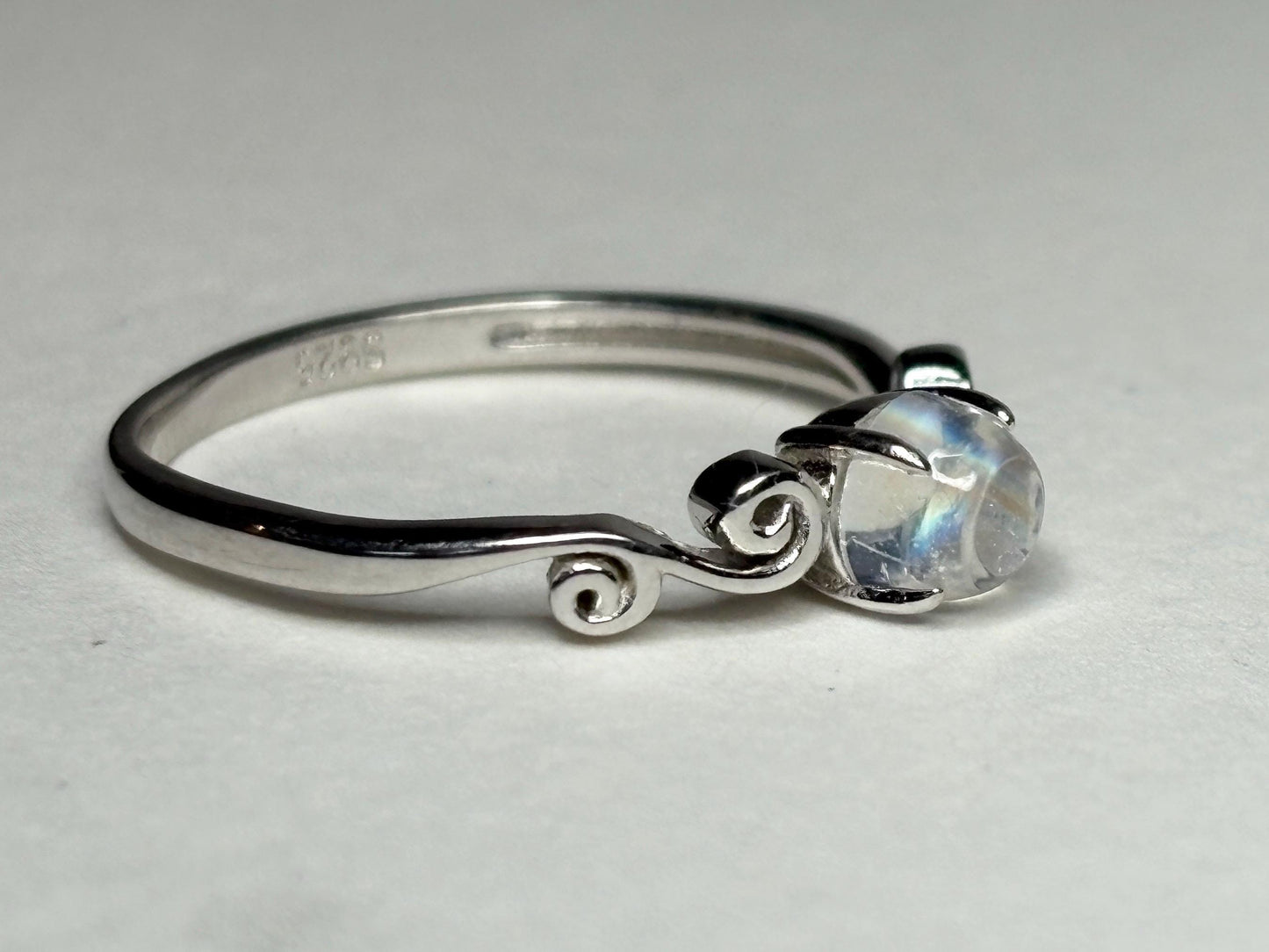 Sterling silver ring with a rainbow moonstone cabochon and swirl details.