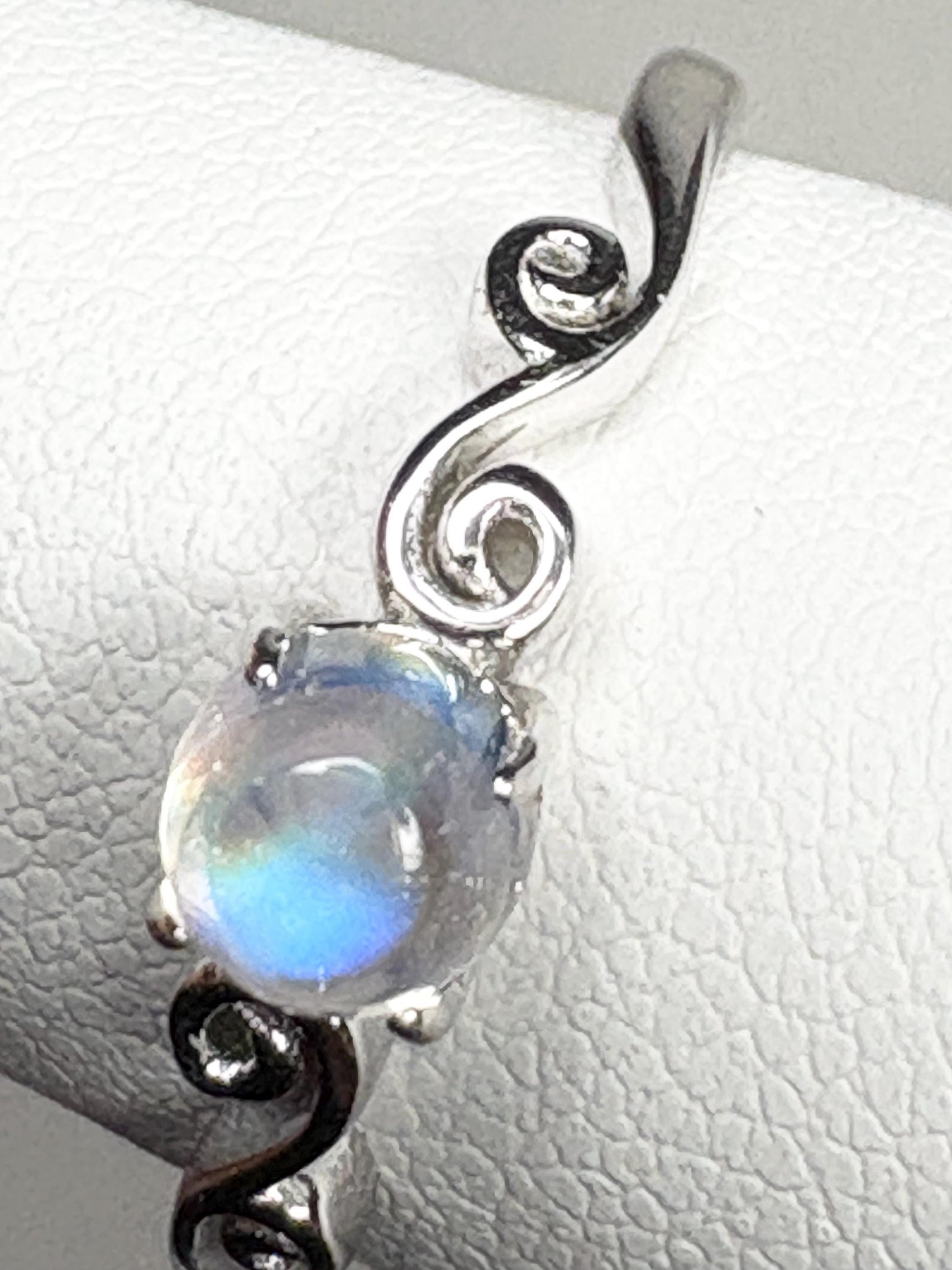 Sterling silver ring with a rainbow moonstone cabochon and swirl design.