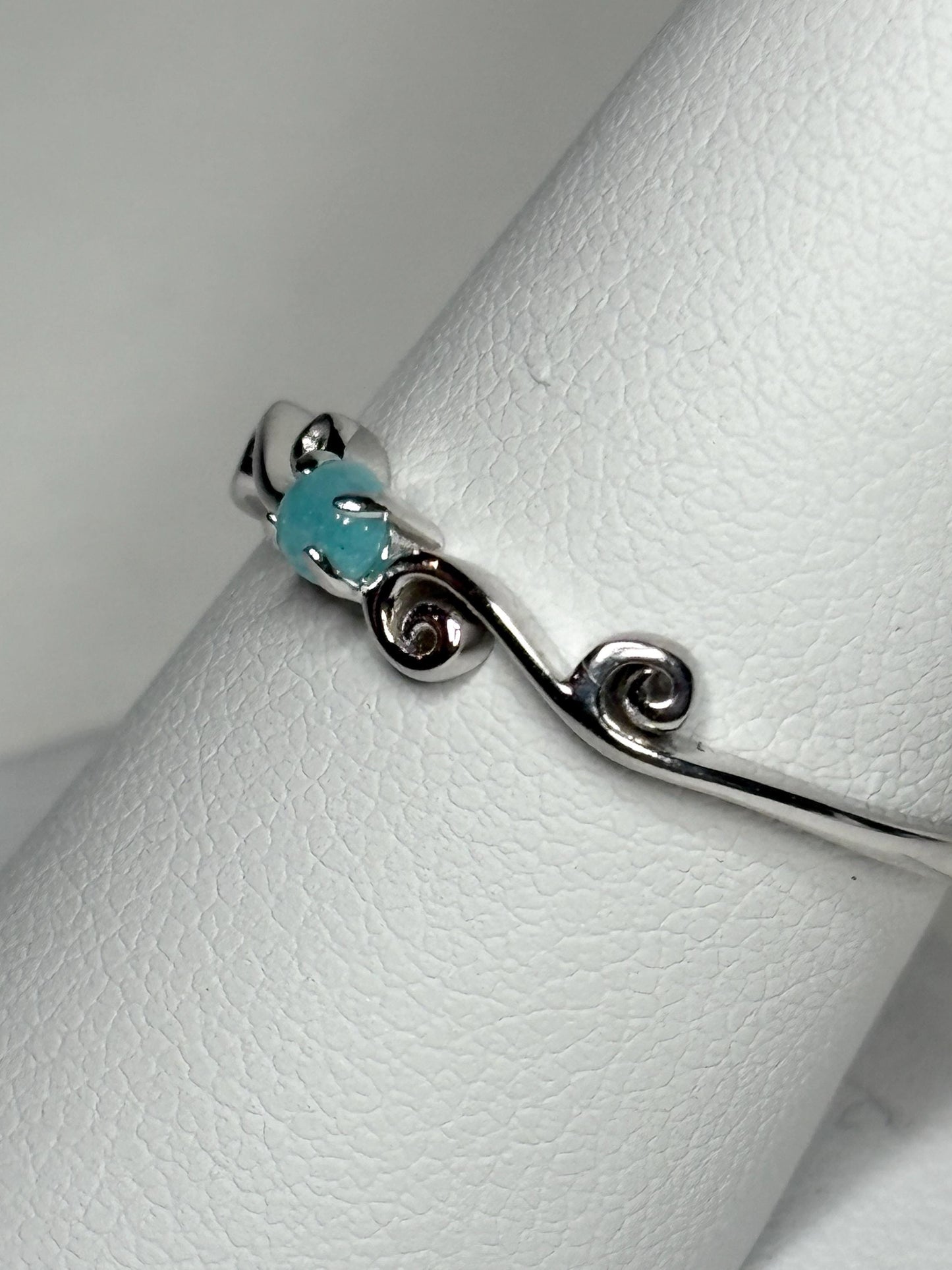 Sterling silver ring with a blue Paraiba tourmaline and swirl design.