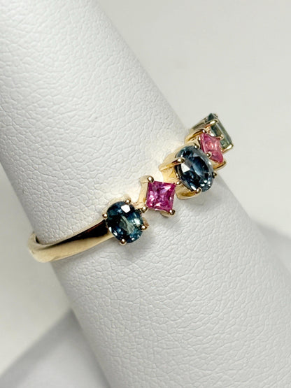 A 9k gold band ring with oval steel blue and square pink sapphires.
