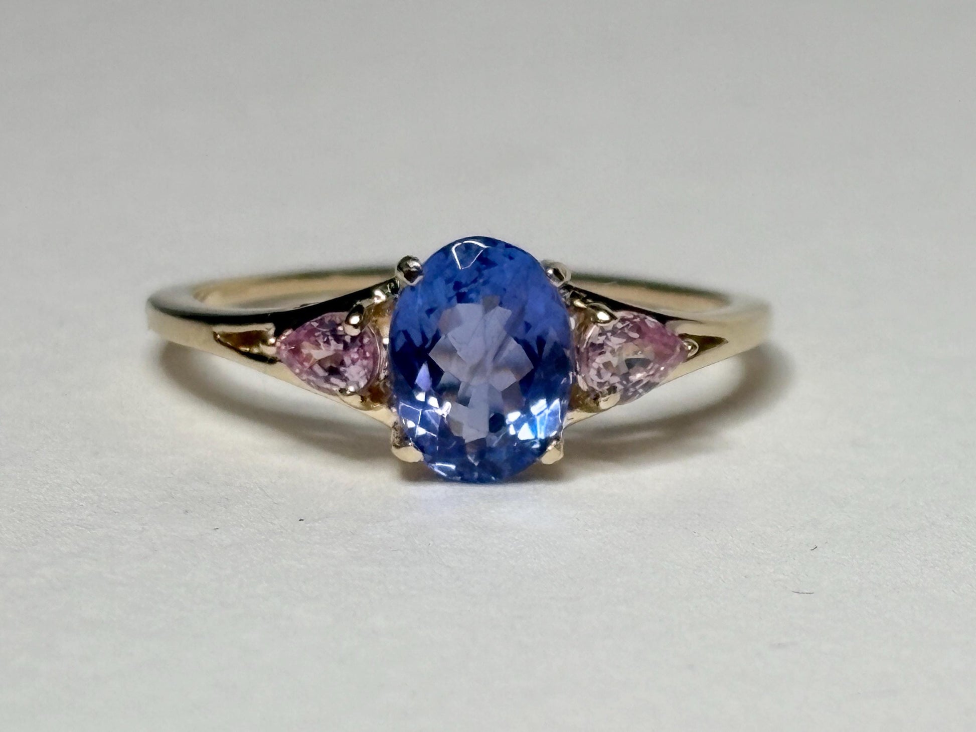 A 9k gold ring with an oval tanzanite and pear-shaped pink sapphires.