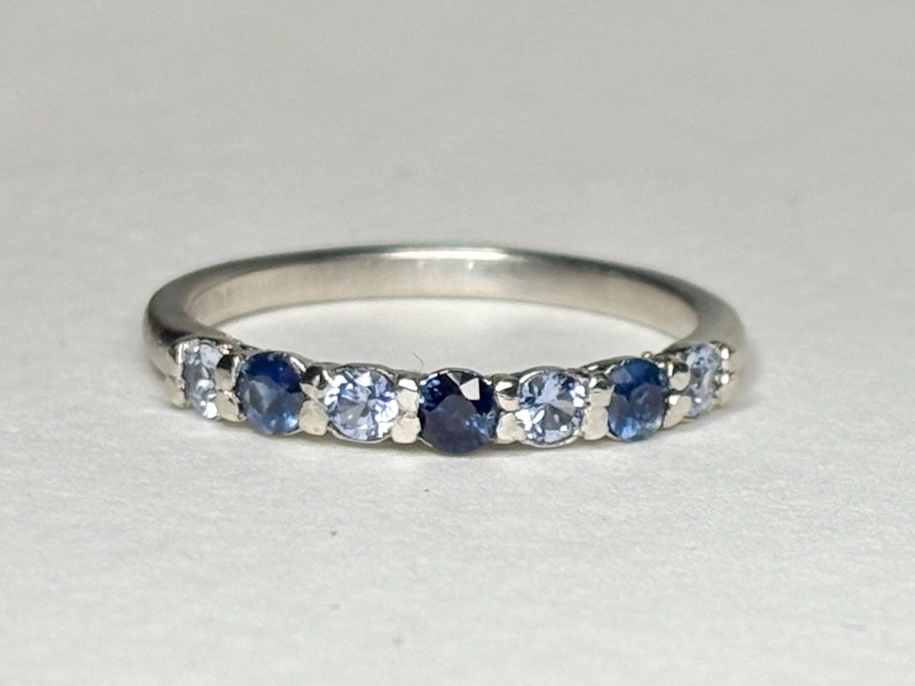 Sterling silver band ring with alternating blue and light blue sapphires.