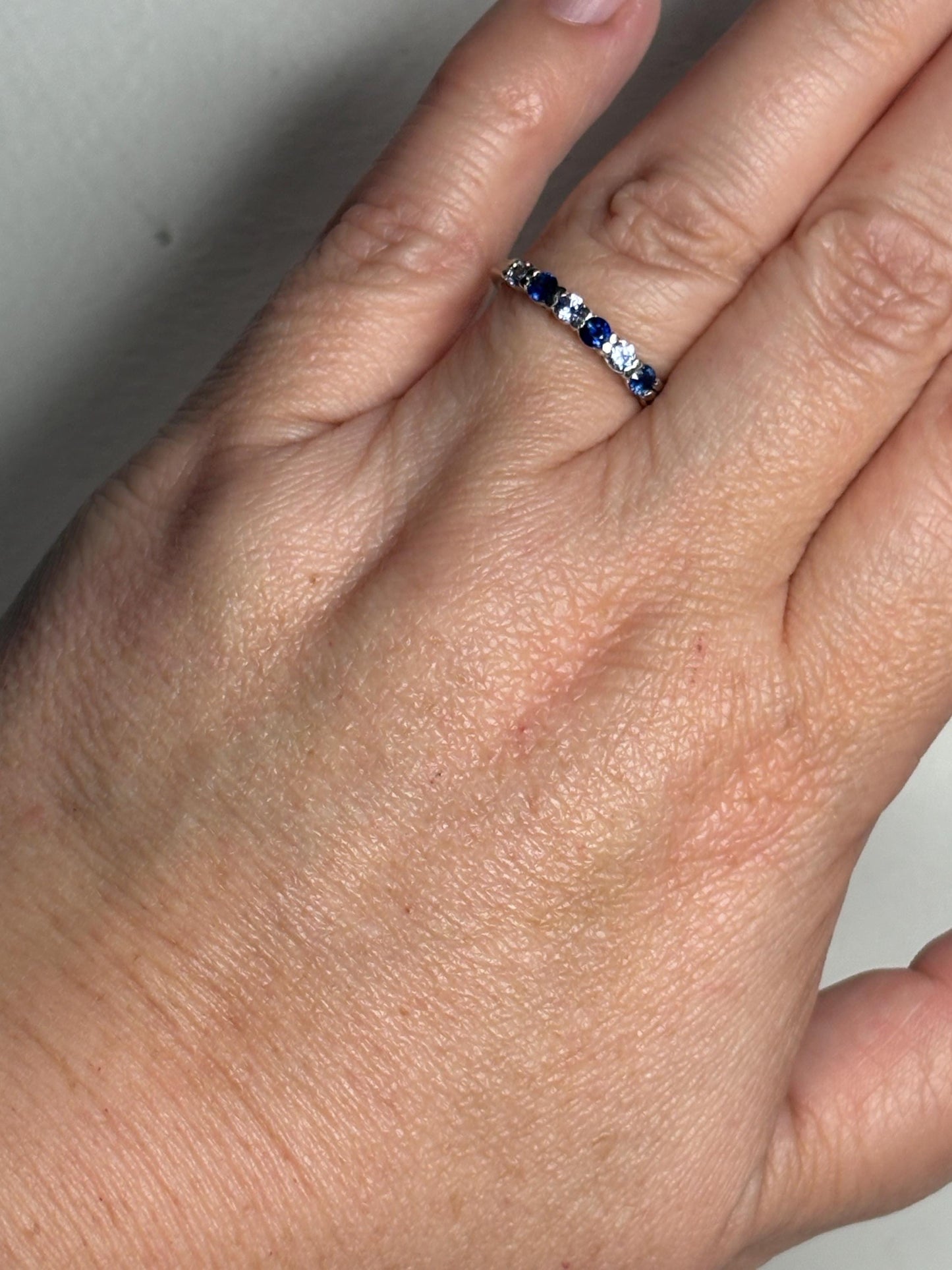 Sterling silver band ring with alternating blue and light blue sapphires.