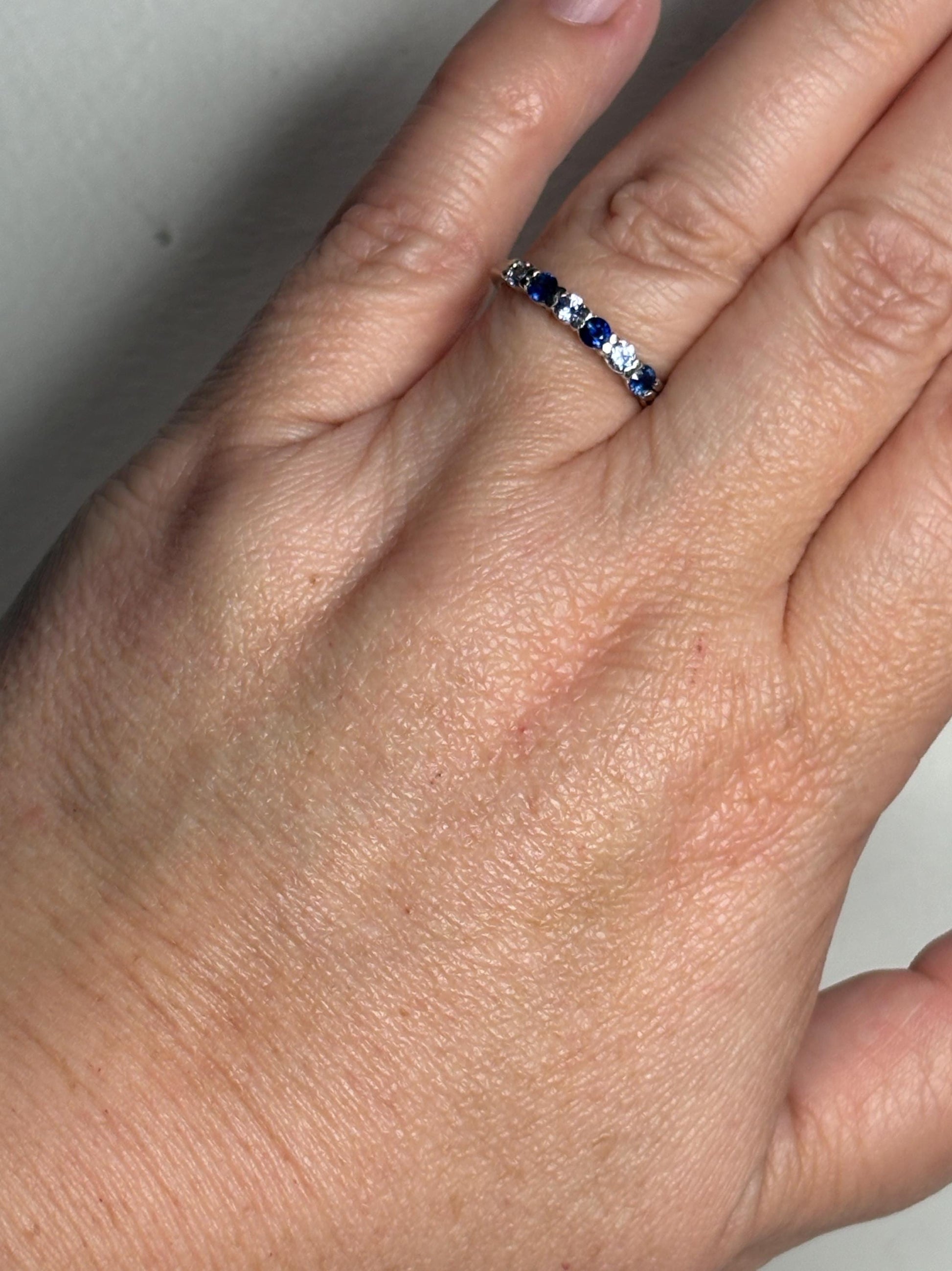 Sterling silver band ring with alternating blue and light blue sapphires.