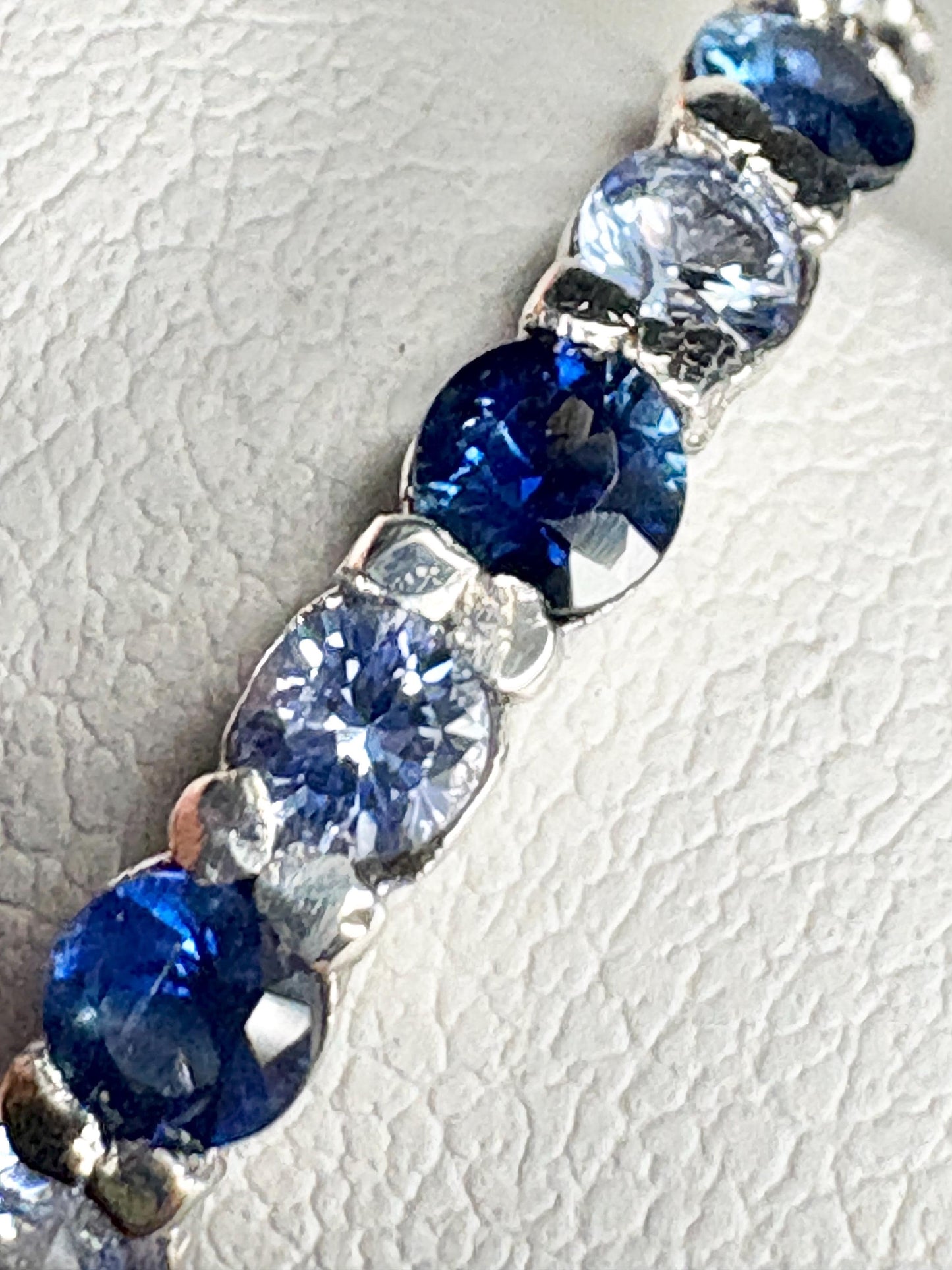 Sterling silver band ring with a row of blue and light blue sapphires.