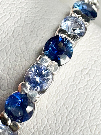 Sterling silver band ring with a row of blue and light blue sapphires.
