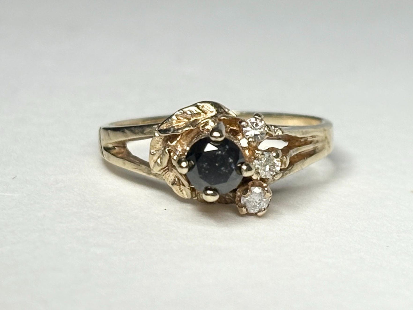 10k yellow gold ring with a black diamond center and three small white diamonds.