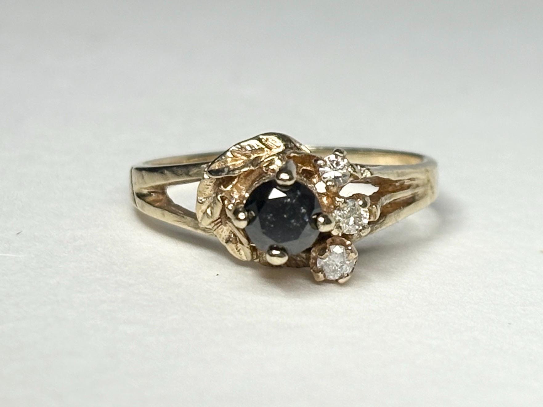 10k yellow gold ring with a black diamond center and three small white diamonds.