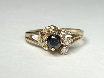 10k yellow gold ring with a black diamond center and three small white diamonds.