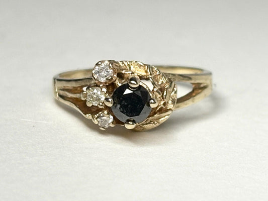 10k yellow gold ring with a black diamond and three white diamonds in a leaf design.