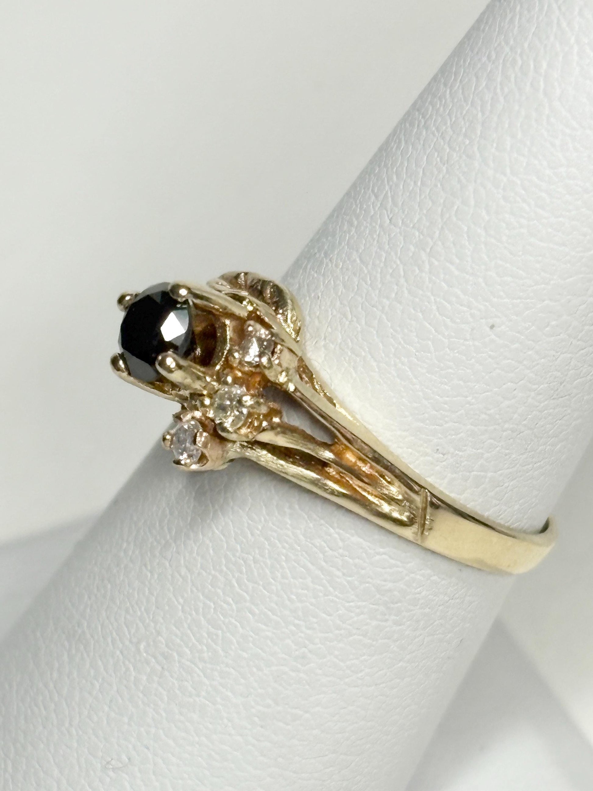 A 10k yellow gold ring with a black diamond and smaller white diamonds.
