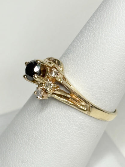 A 10k yellow gold ring with a black diamond and smaller white diamonds.