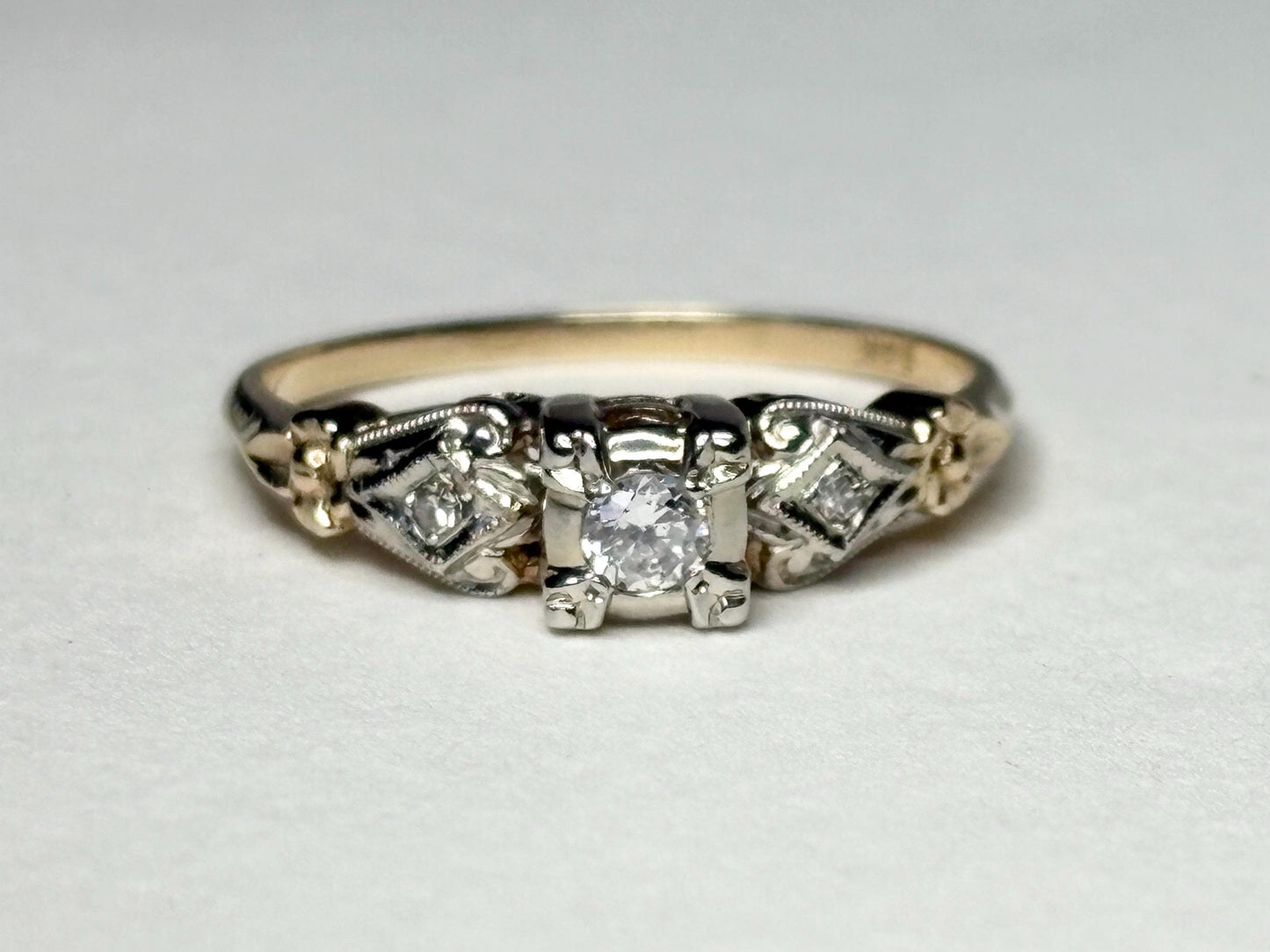Vintage two-tone 14k gold ring with a central diamond and two side diamonds.