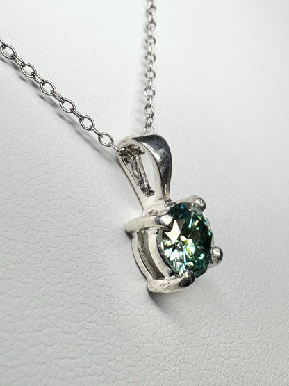 Sterling silver pendant necklace with a teal-green moissanite gemstone.