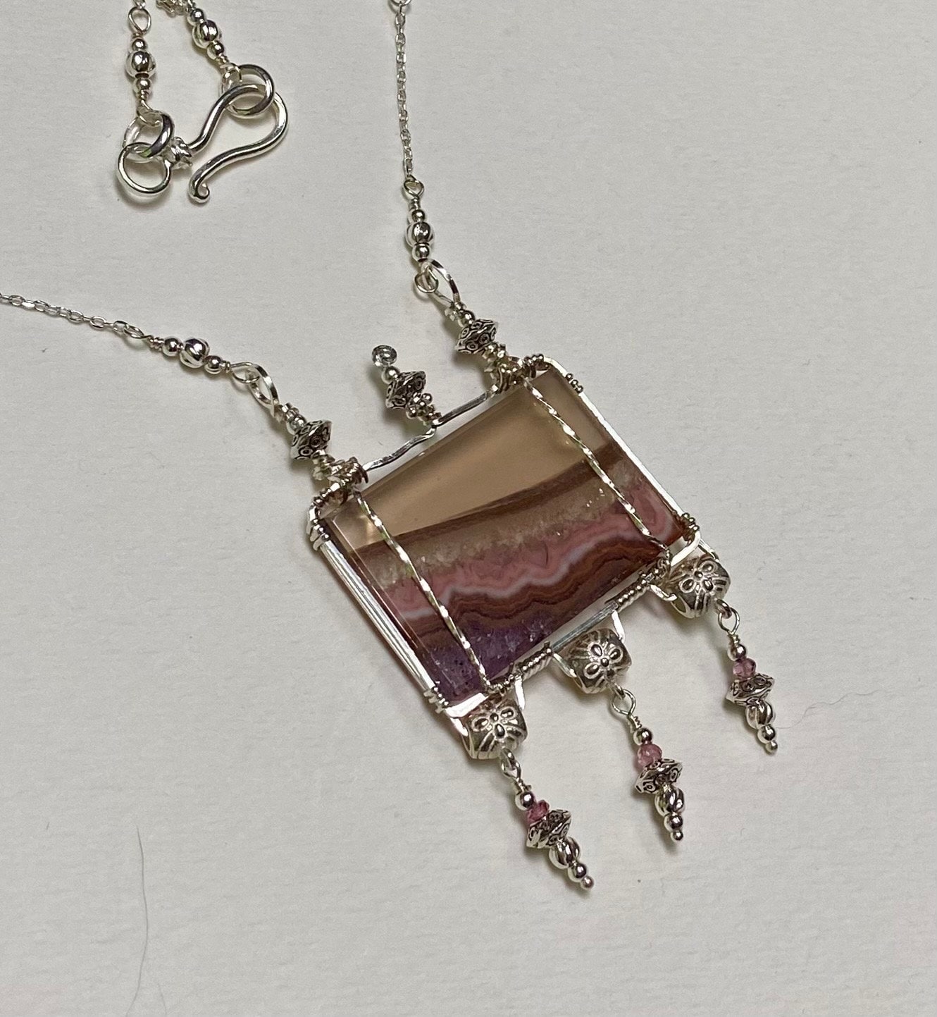 Sterling silver necklace with a rectangular agate and amethyst pendant and pink spinel accents.