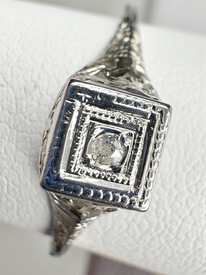 Art Deco 18k gold ring with a small old mine cut diamond and filigree details.