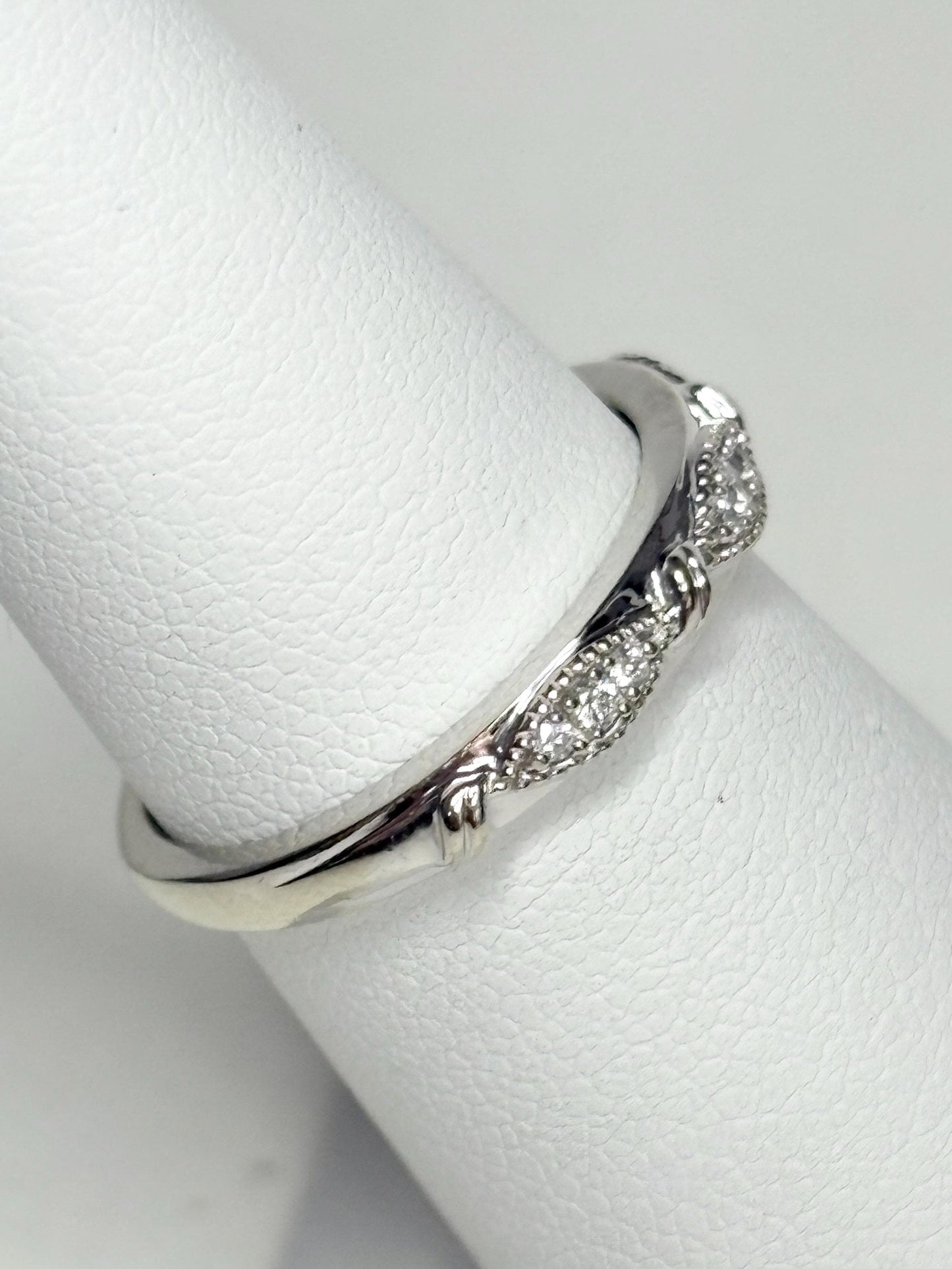 A 10k white gold band ring with diamonds and milgrain detail.