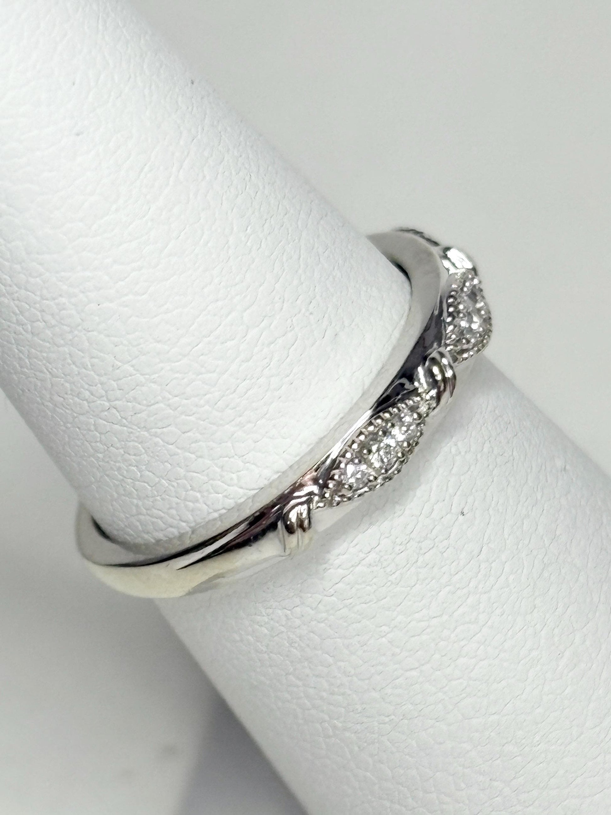 A 10k white gold band ring with diamonds and milgrain detail.