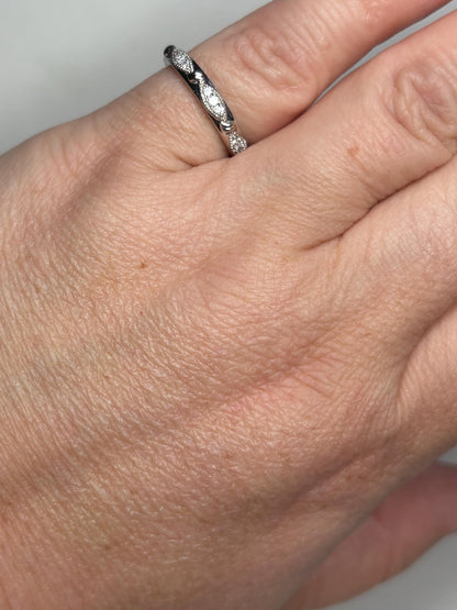 A stackable 10k white gold band ring with diamonds and milgrain detail.