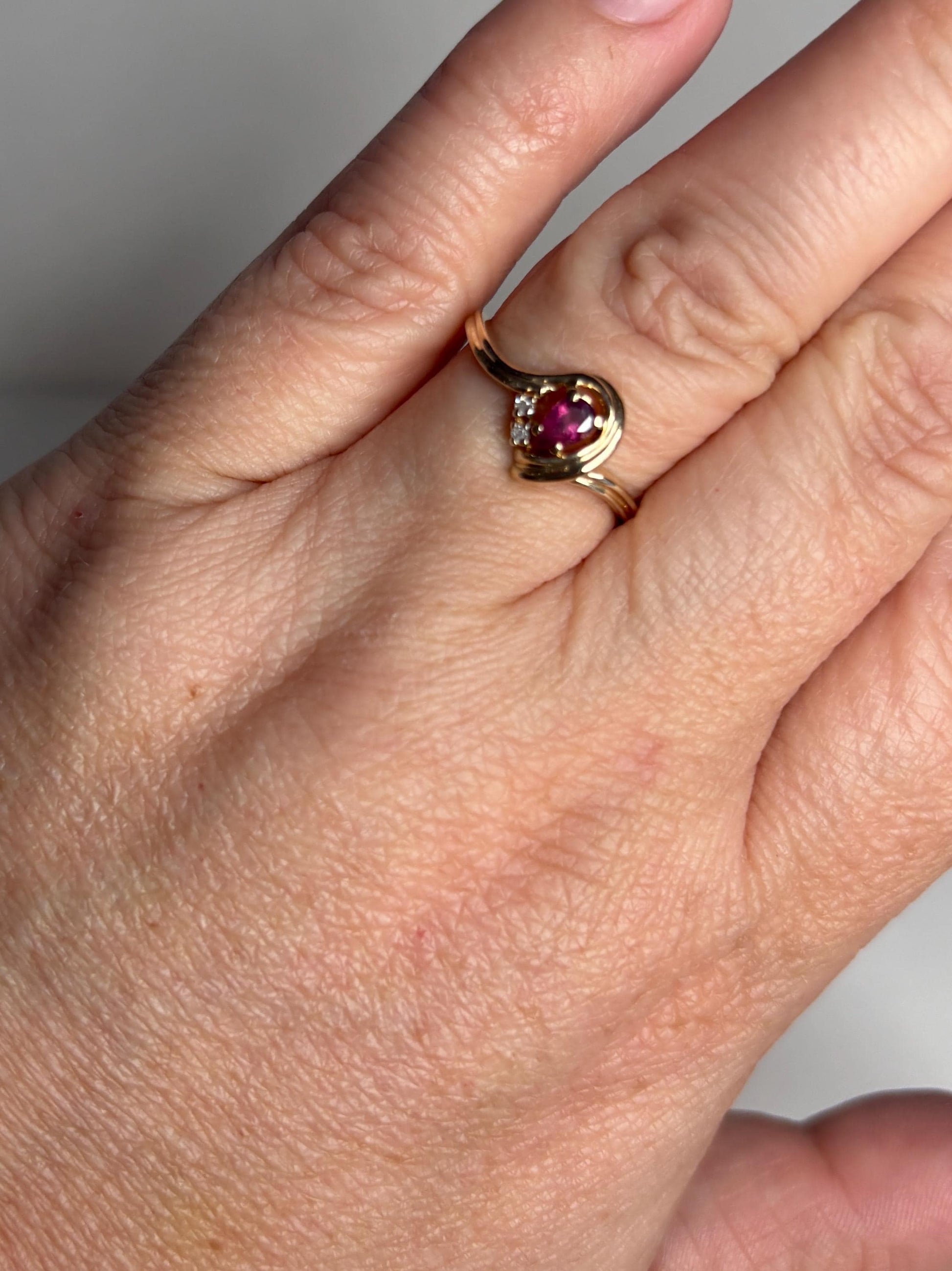 10k gold ring with a pear-shaped ruby and diamond accents.
