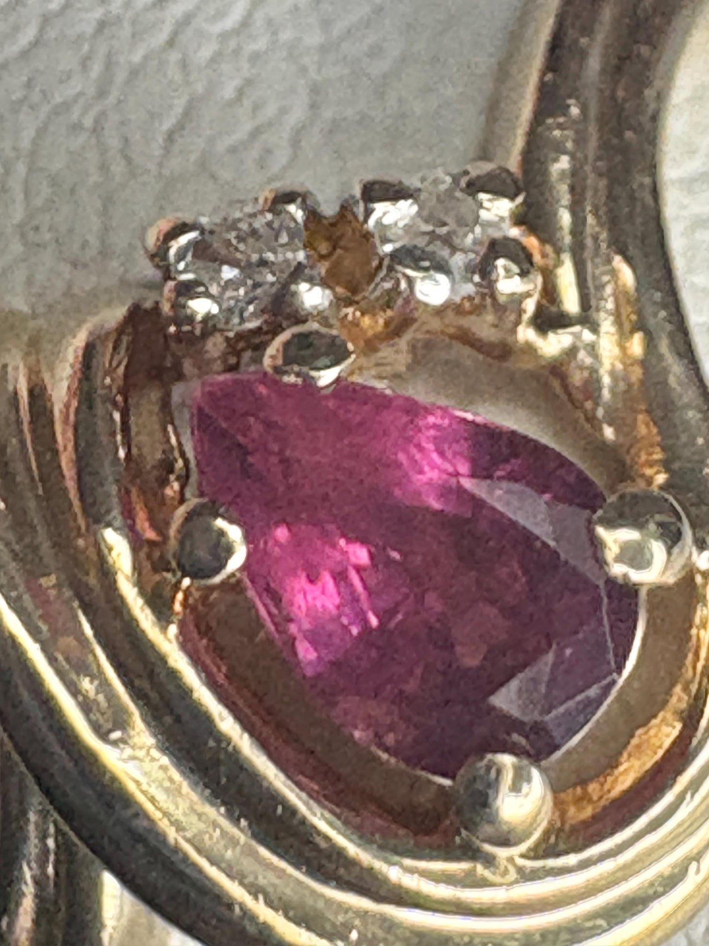 10k gold ring with a pear-shaped ruby and diamond accents.