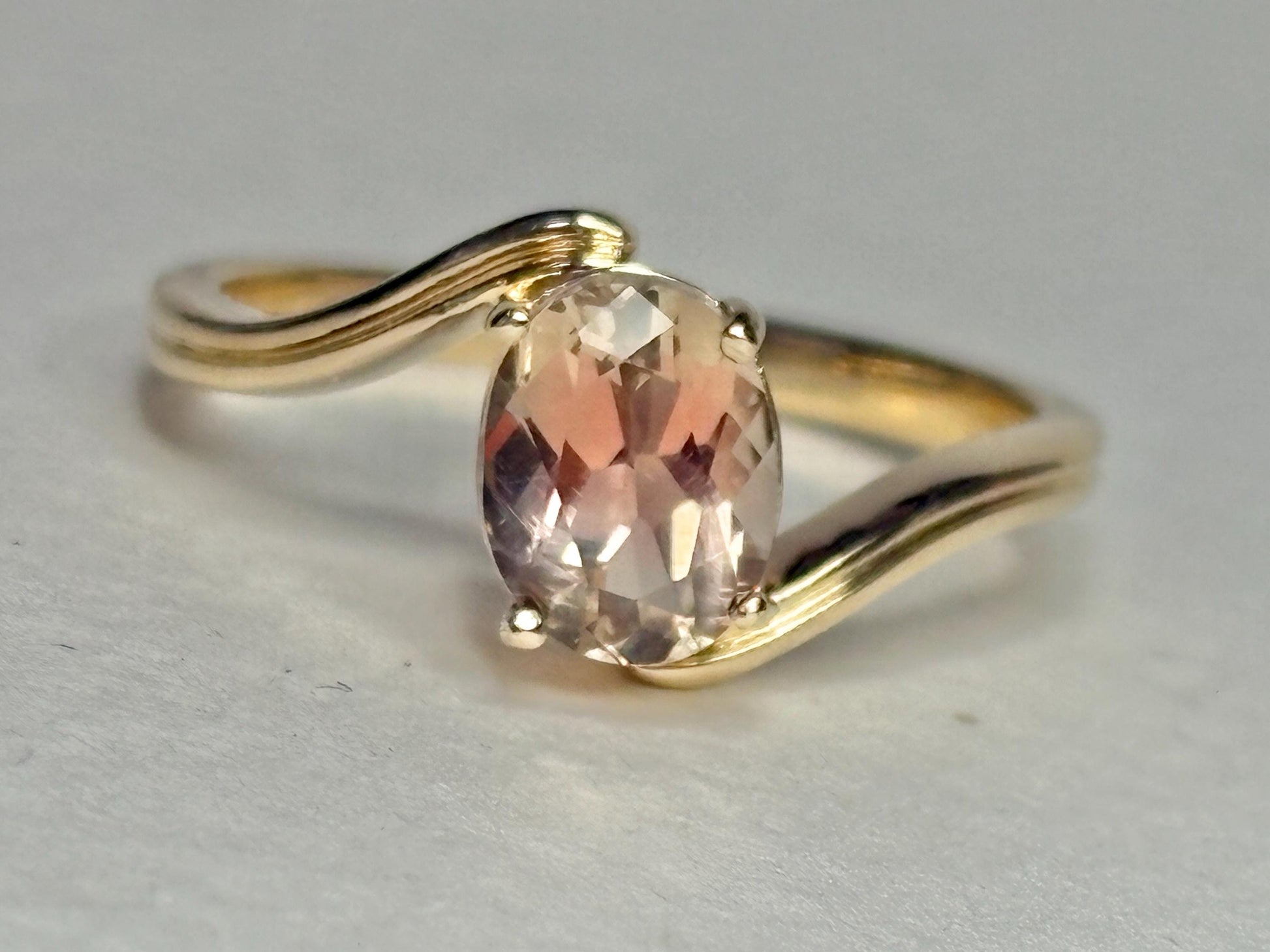 A 14k gold bypass ring with a light peach oval Oregon sunstone.