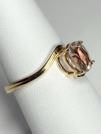 A 14k gold bypass ring with a light peach Oregon sunstone.