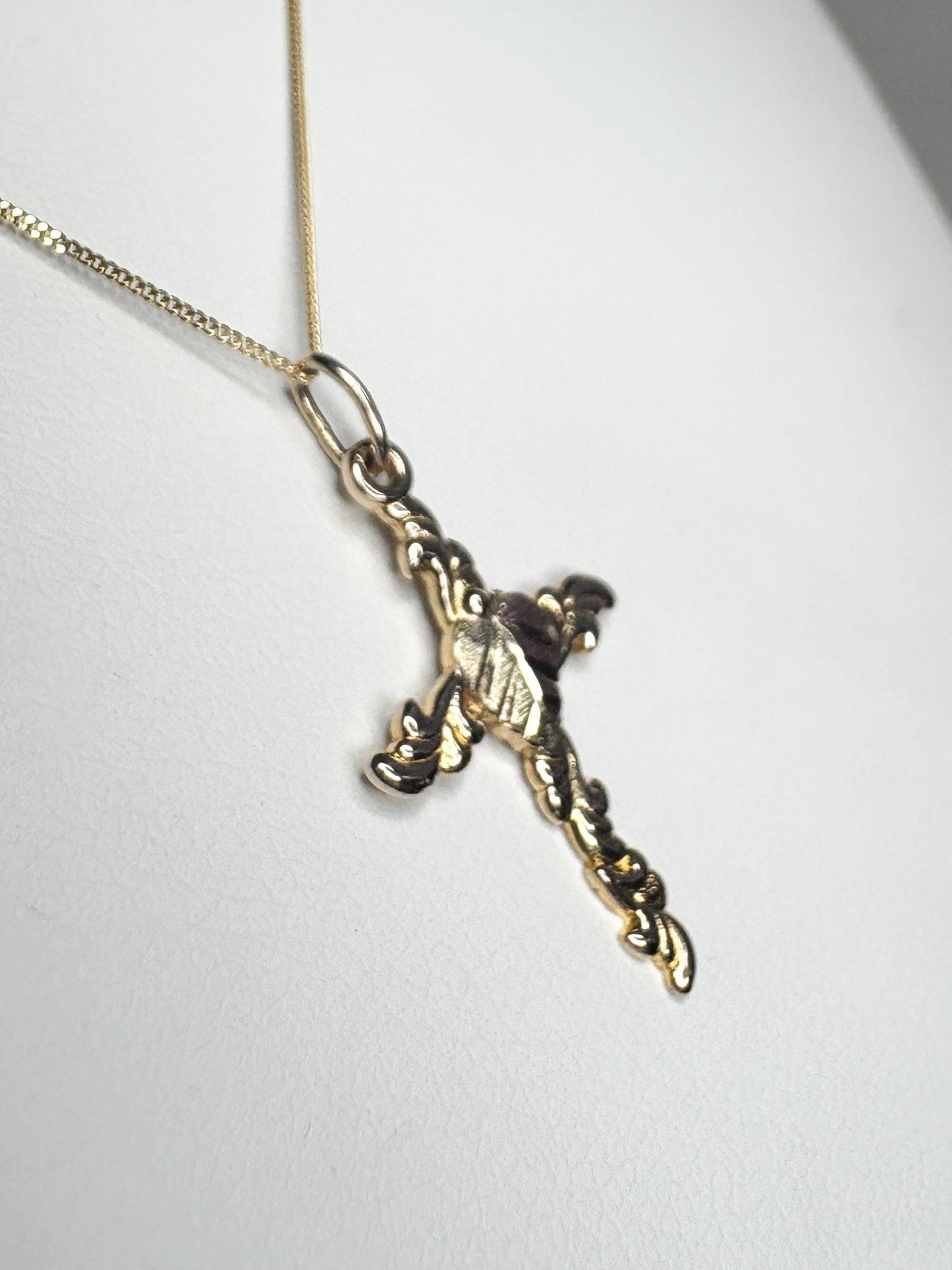 A gold cross pendant on a gold chain.
