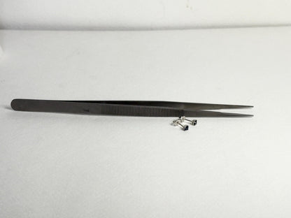 Dark blue sapphire stud earrings in 14k white gold with tweezers.