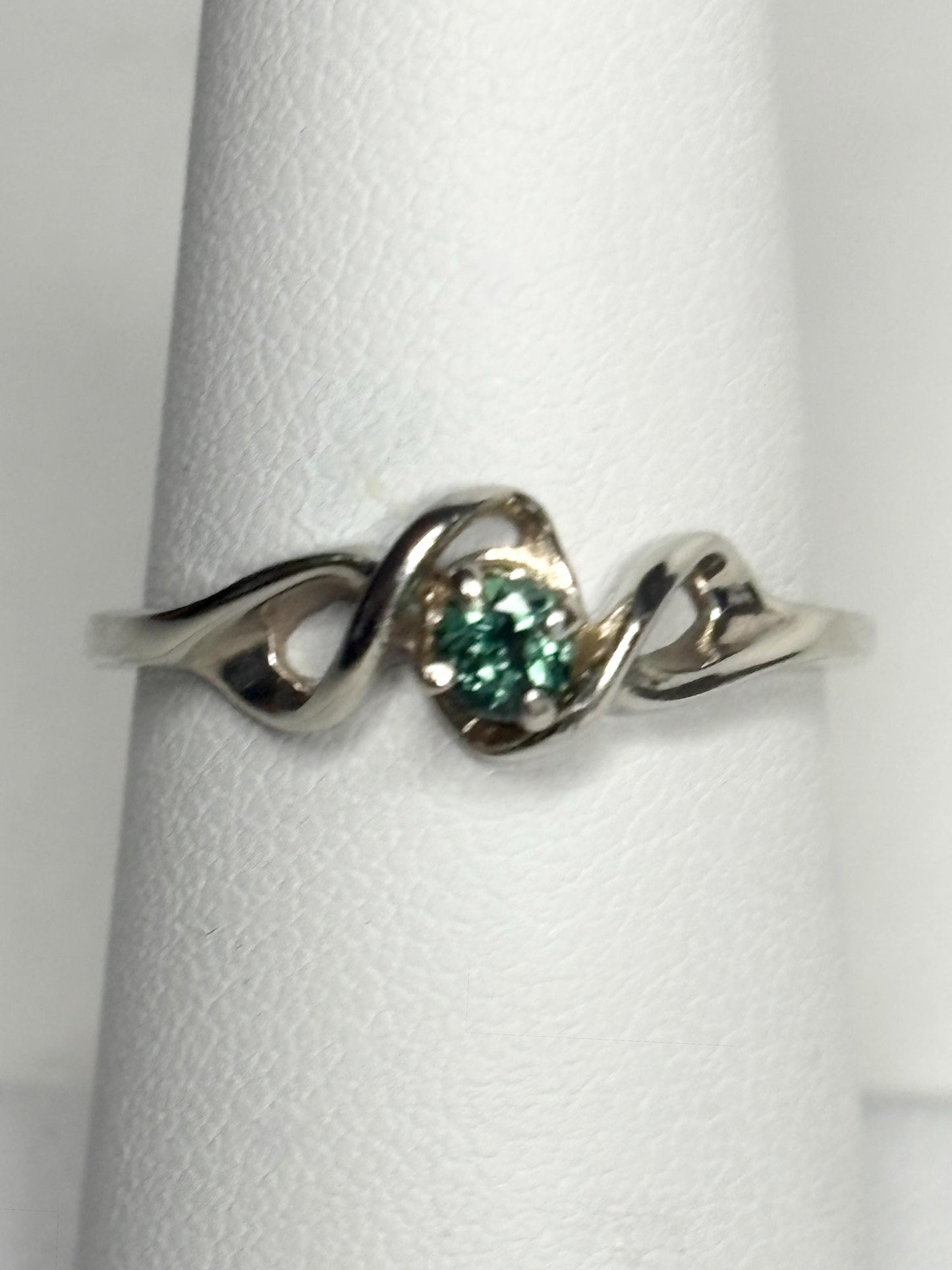 A 10k white gold band ring with a round blue-green tourmaline.