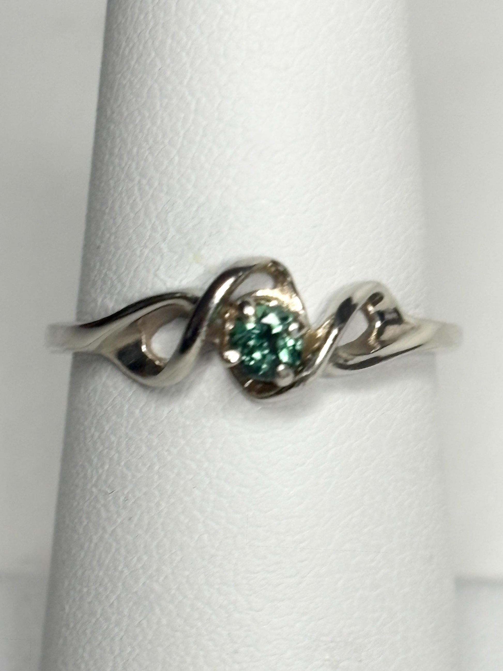 A 10k white gold band ring with a round blue-green tourmaline.