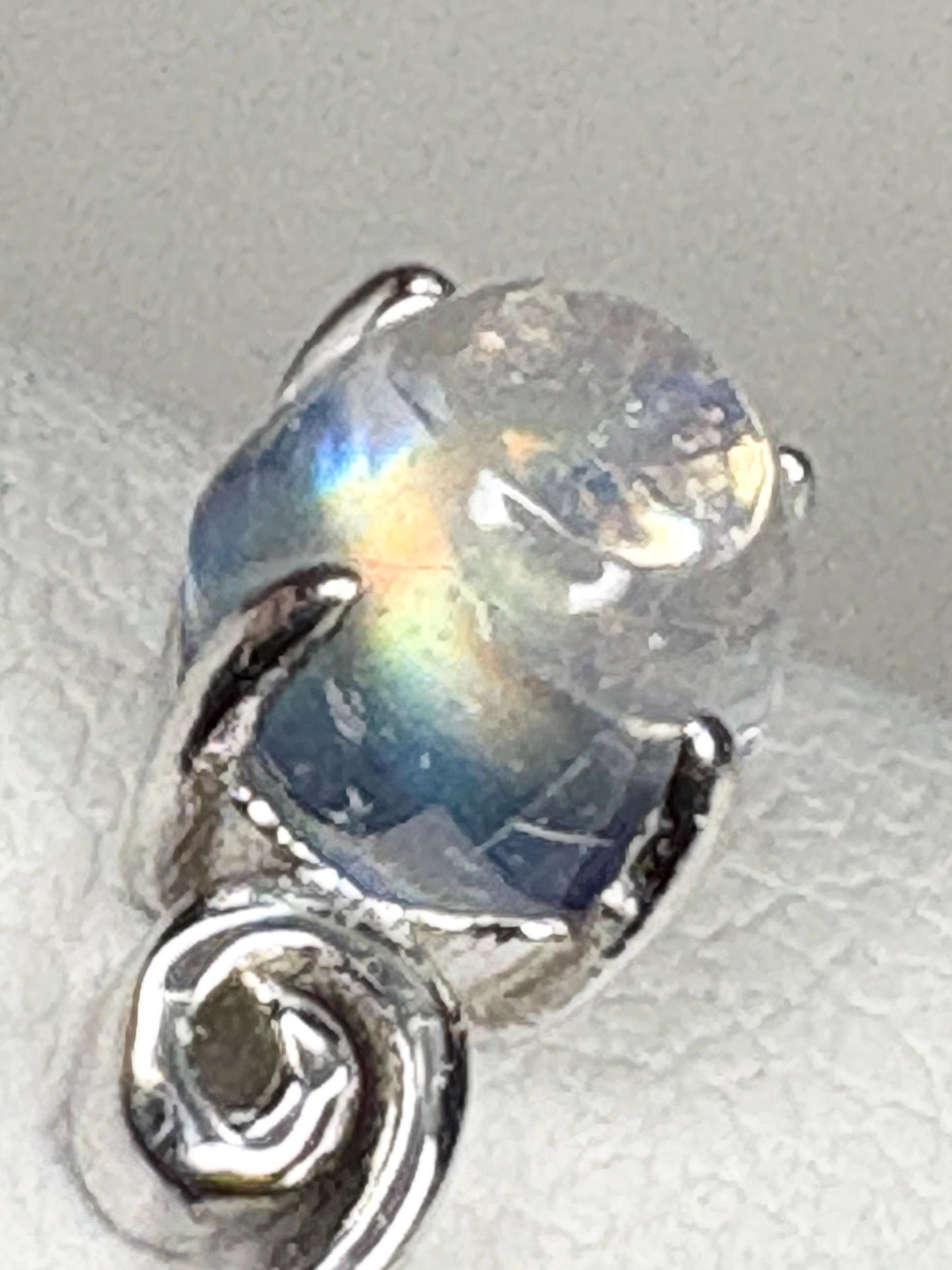 Sterling silver ring with a rainbow moonstone cabochon and a swirl design.