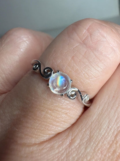 Sterling silver ring with a rainbow moonstone cabochon and swirl details.
