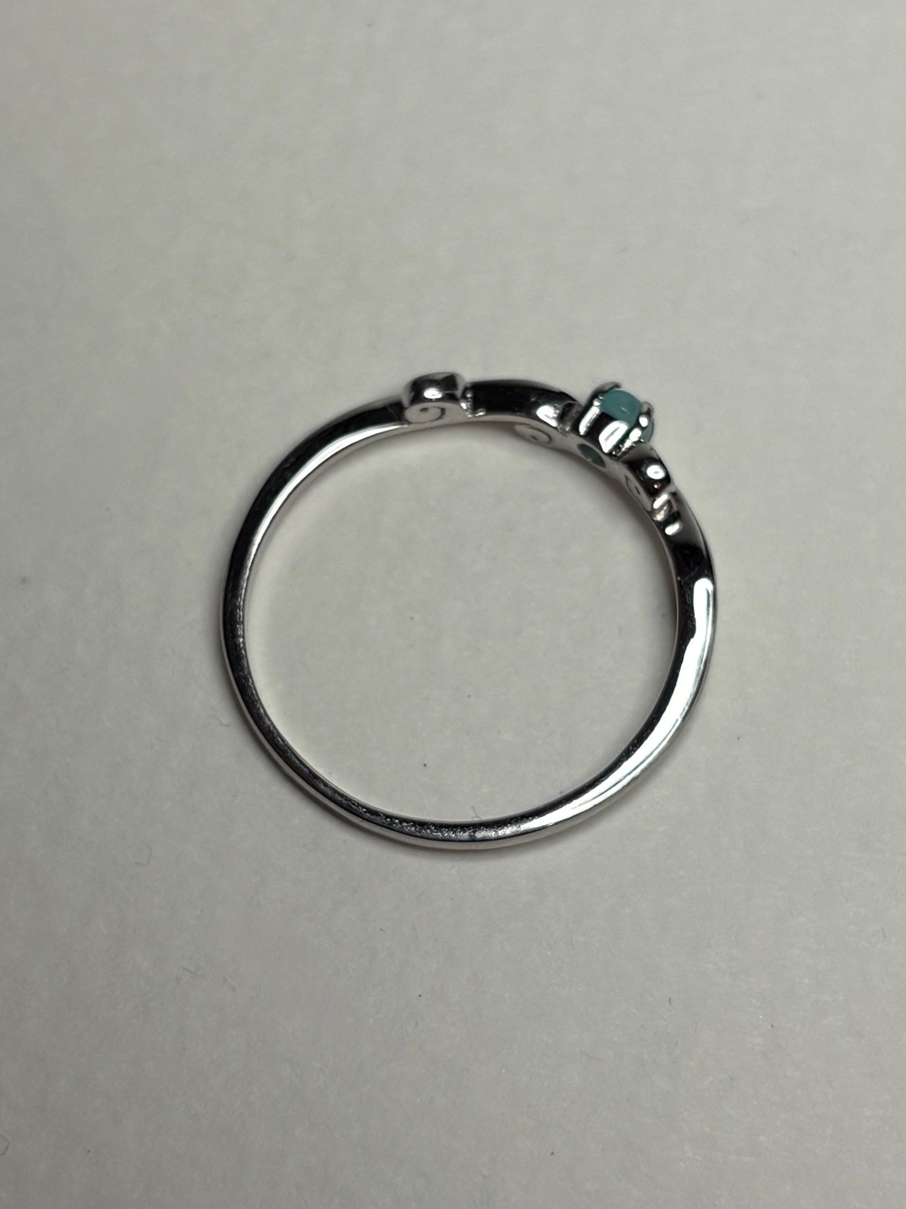Sterling silver ring with a swirl design and a small blue gemstone.