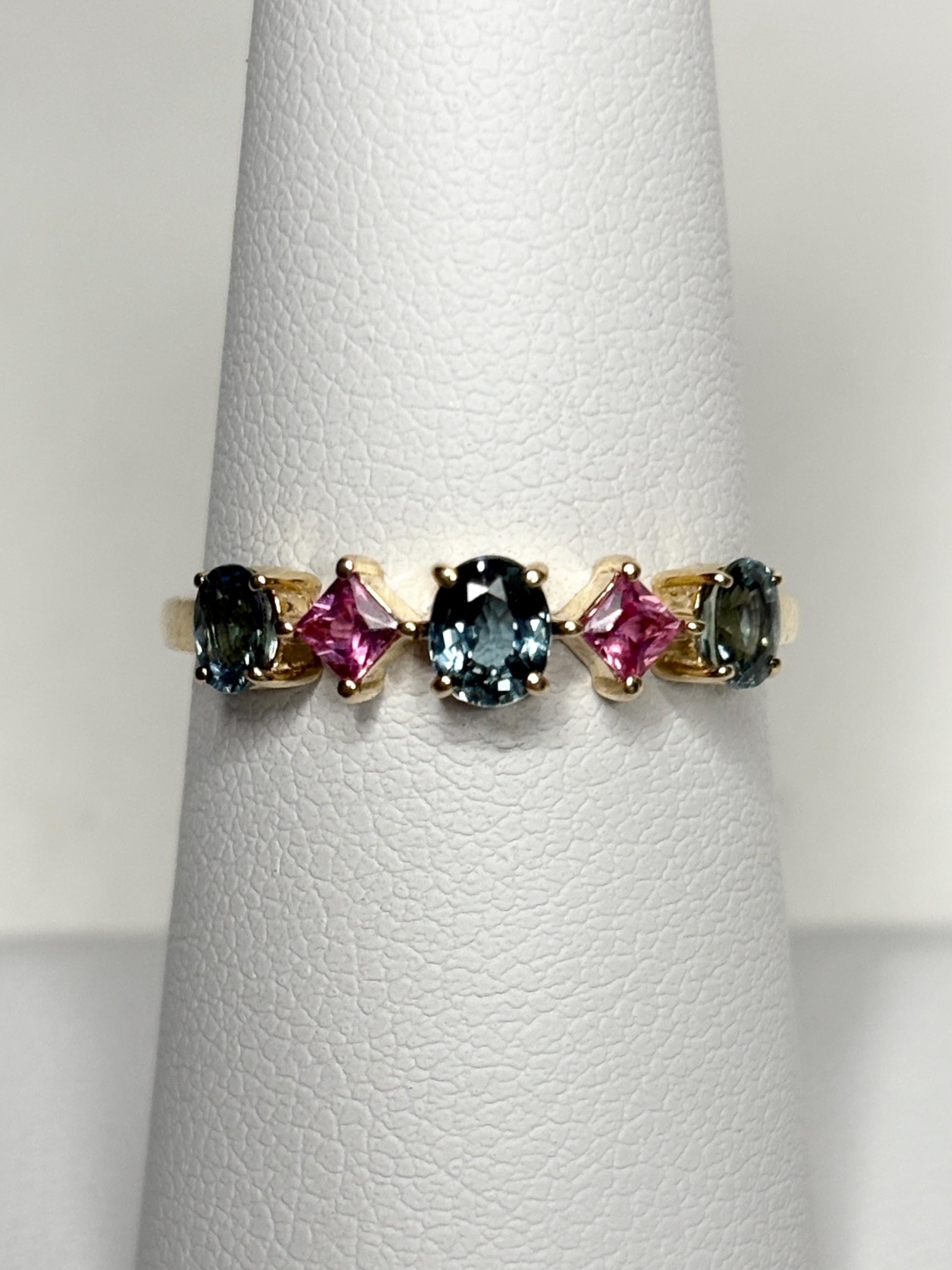 A 9k gold band ring with oval steel blue and square pink sapphires.