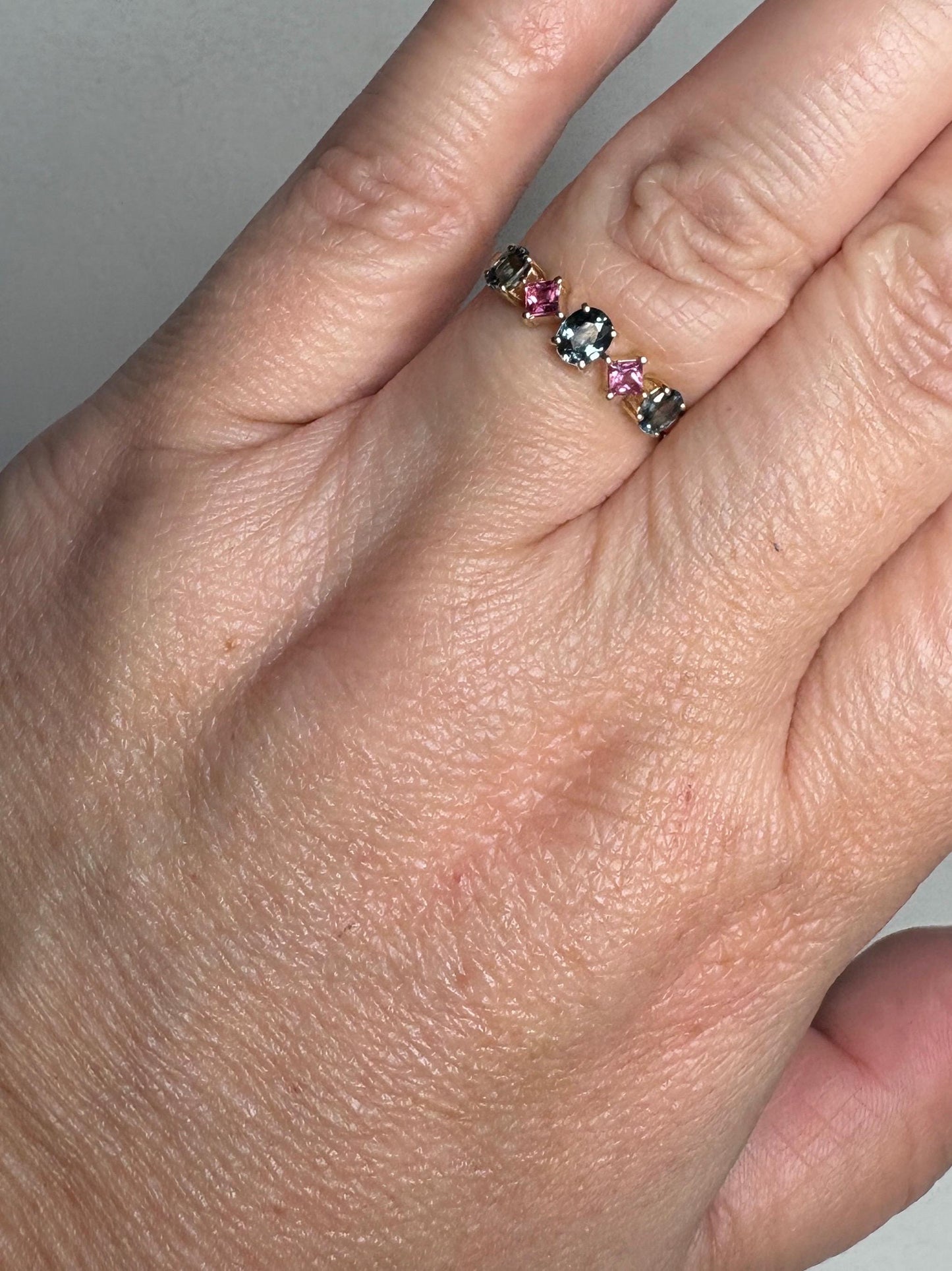 9k gold band ring with oval steel blue and square pink sapphires.