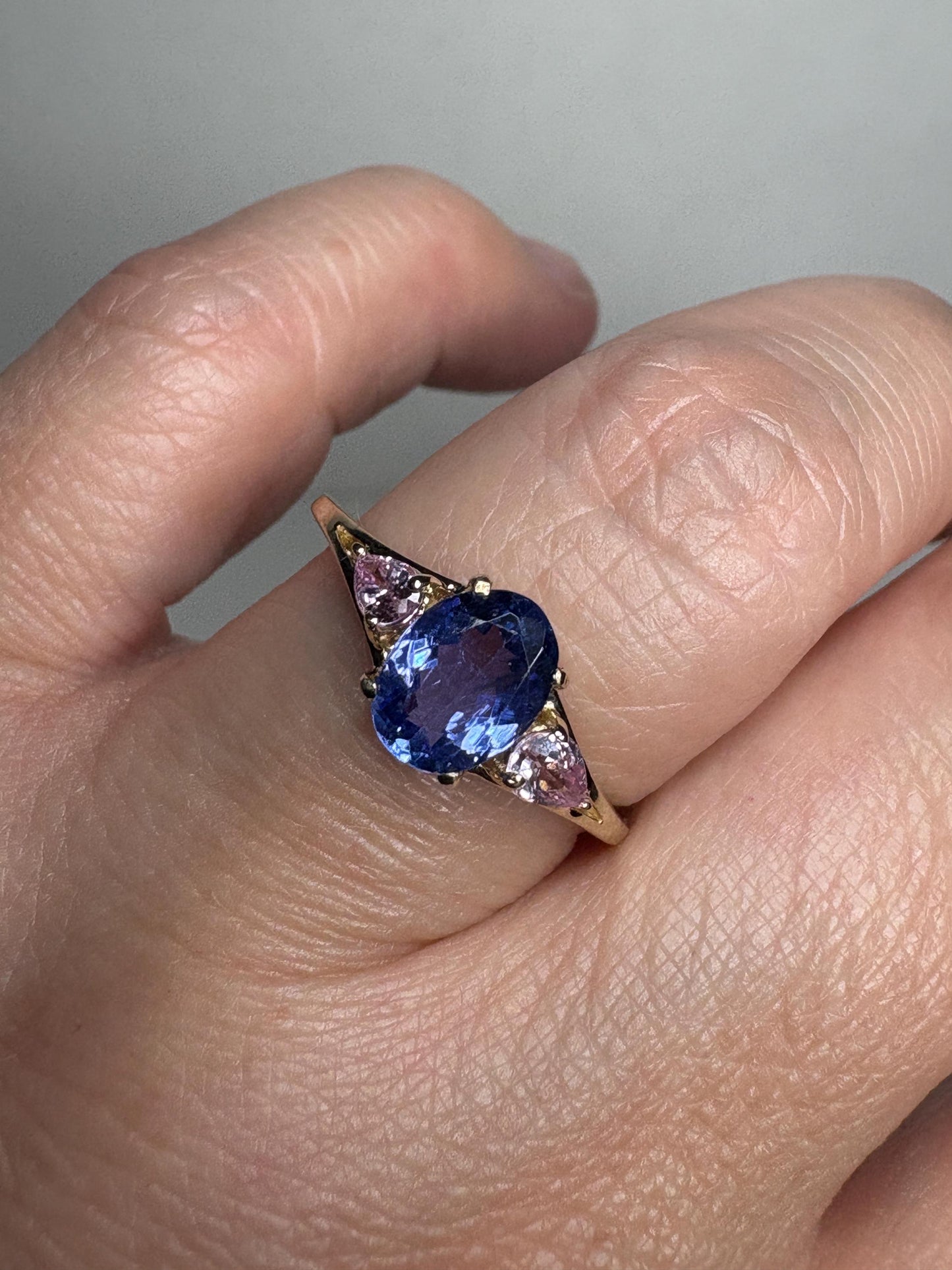 A 9k gold ring with an oval tanzanite and pear-shaped pink sapphires.